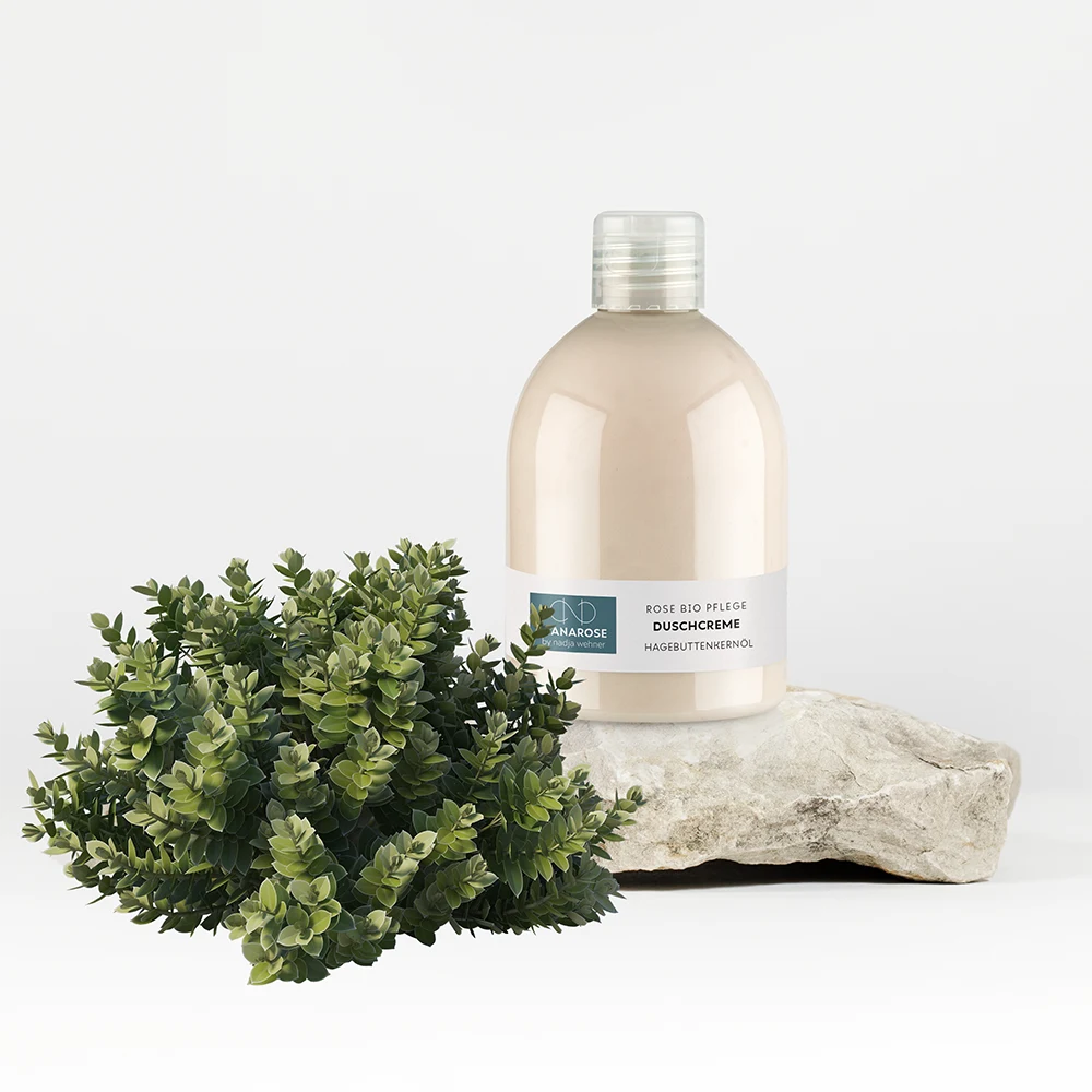 Eine Flasche Manarose Biokosmetik Duschcreme Hagebuttenkernöl neben einer Pflanze.