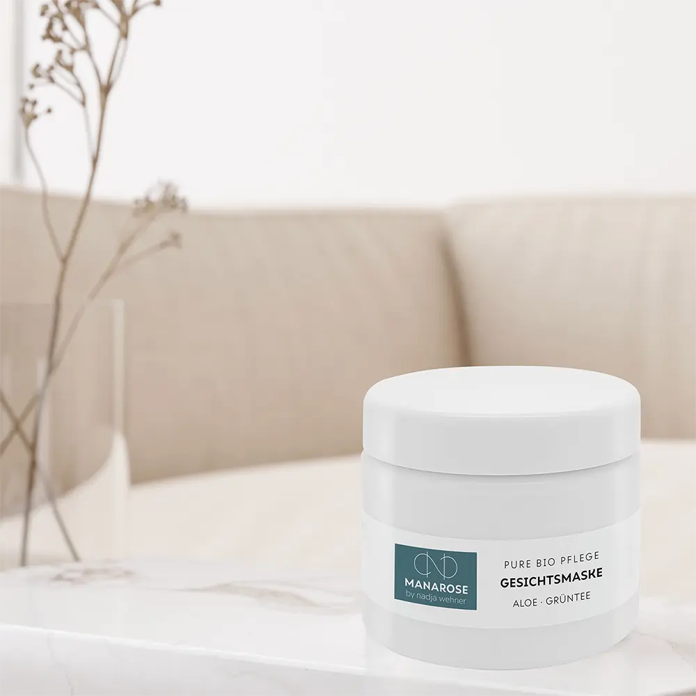 Ein Glas Manarose Biokosmetik Gesichtsmaske Aloe Grüntee Creme steht auf einem Tisch im Wohnzimmer.