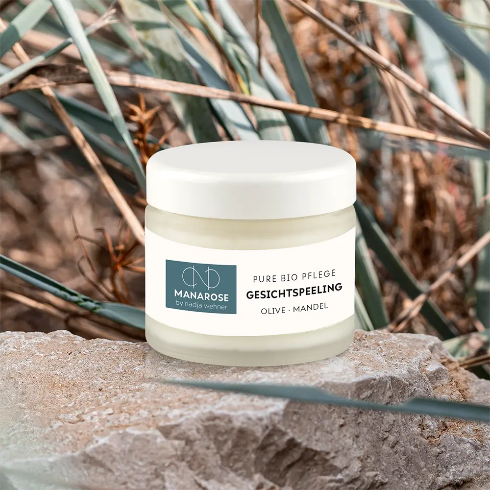 Ein Glas Gesichtspeeling Olive Mandel Gesichtscreme sitzt auf einem Felsen für Reinigung von Manarose Biokosmetik.