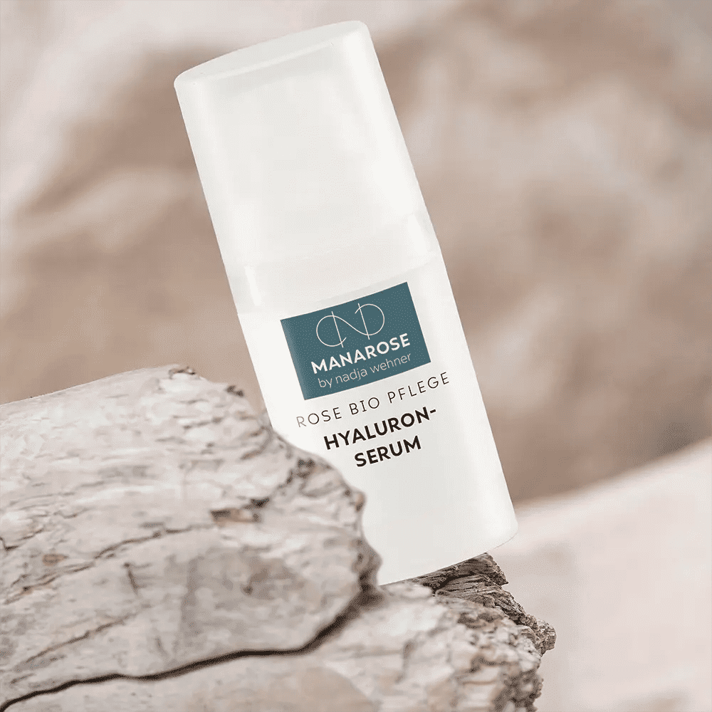 Eine Flasche Hyaluron Serum Rose von Manarose Biokosmetik spendet Feuchtigkeit auf einem Felsen und bekämpft Hautveränderungen.