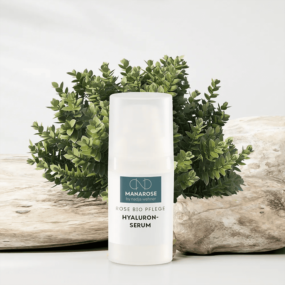 Eine Flasche Hyaluron Serum Rose, speziell von der Marke Manarose Biokosmetik, neben einer Pflanze zur Bekämpfung von Hautalterung.