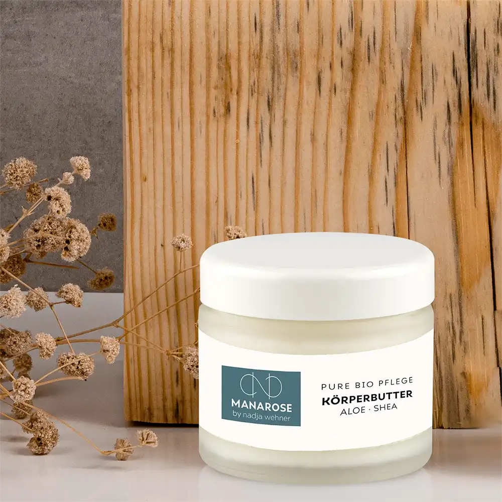 Ein Glas Manarose Biokosmetik Körperbutter Aloe Shea neben einer Holzkiste.