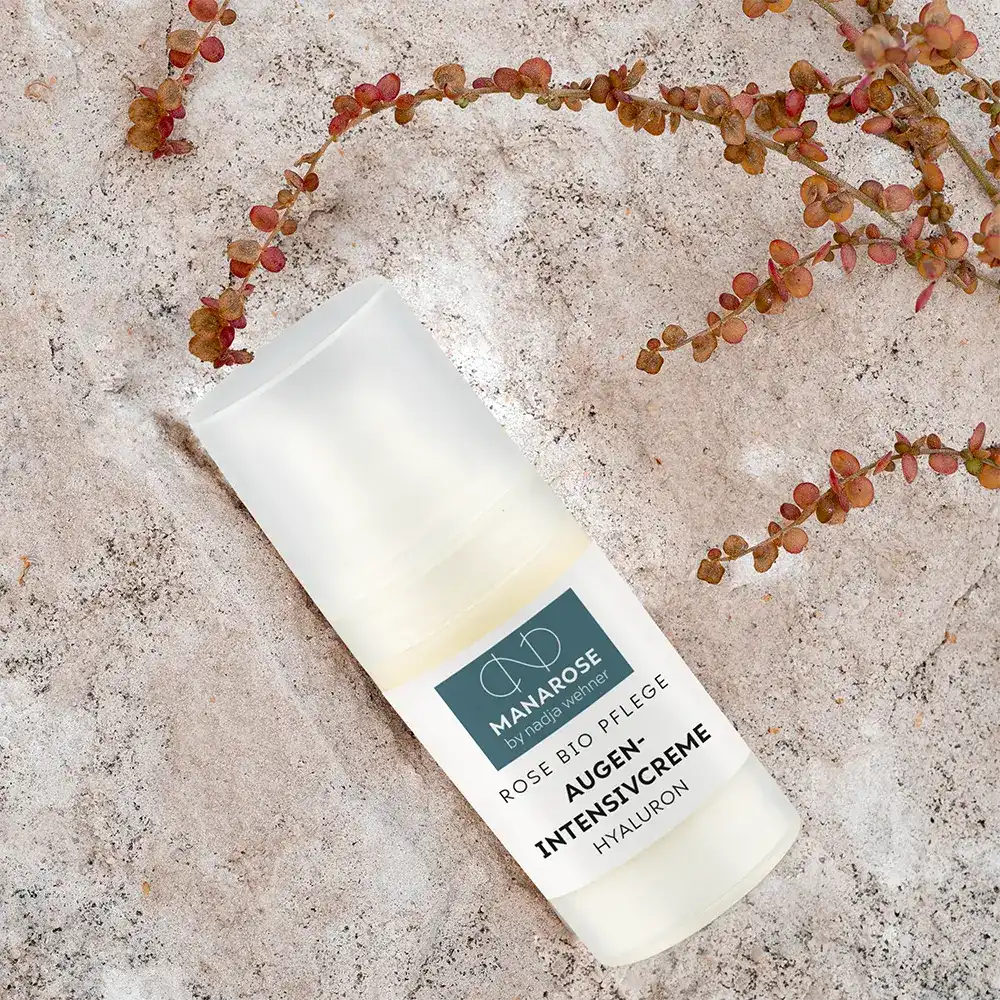 Eine Flasche Manarose Biokosmetik Augen Intensivcreme Hyaluron-Serum auf einem Stein sitzend, für eine frischere und jugendlichere Augenpartie.