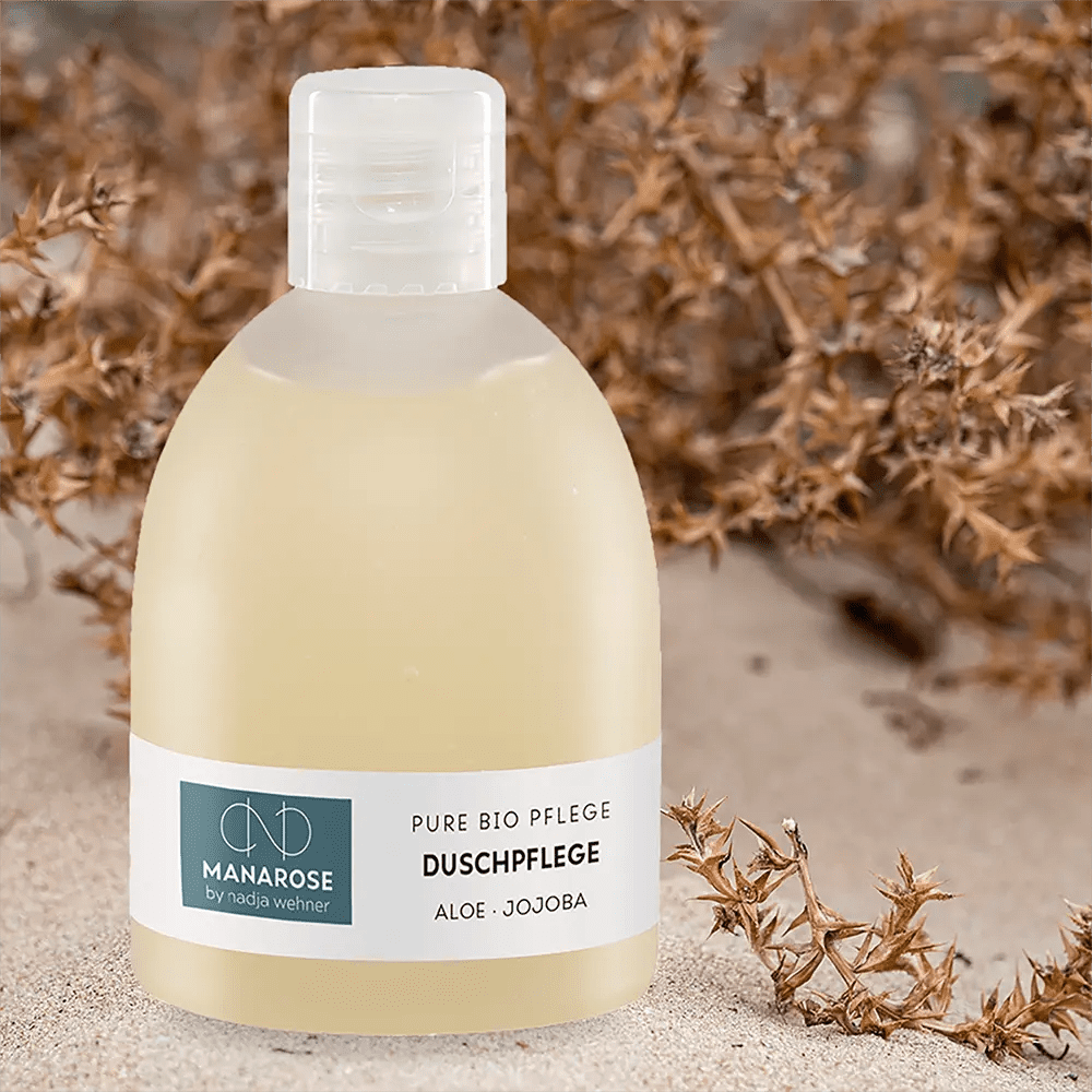 Eine Flasche Duschpflege Aloe Jojoba von Manarose Biokosmetik auf einem Sanddünen.