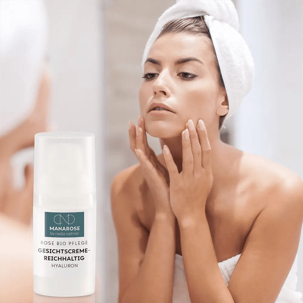 Eine Frau untersucht ihr Gesicht im Spiegel und konzentriert sich dabei auf Manarose Biokosmetik Gesichtscreme Reichhaltig Hyaluron und strahlende Haut.