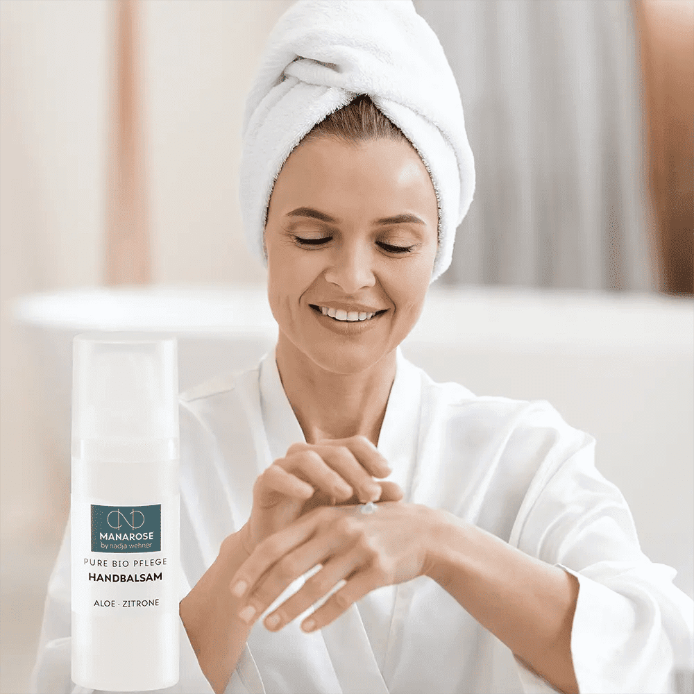 Eine Frau mit einer Flasche Manarose Biokosmetik Handbalsam Aloe Zitrone.