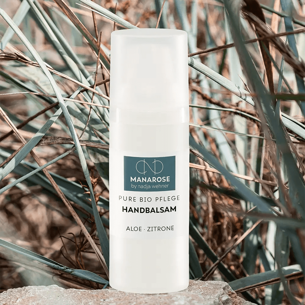 Eine Flasche Handbalsam Aloe Zitrone Handcreme von Manarose Biokosmetik sitzt auf Felsen.