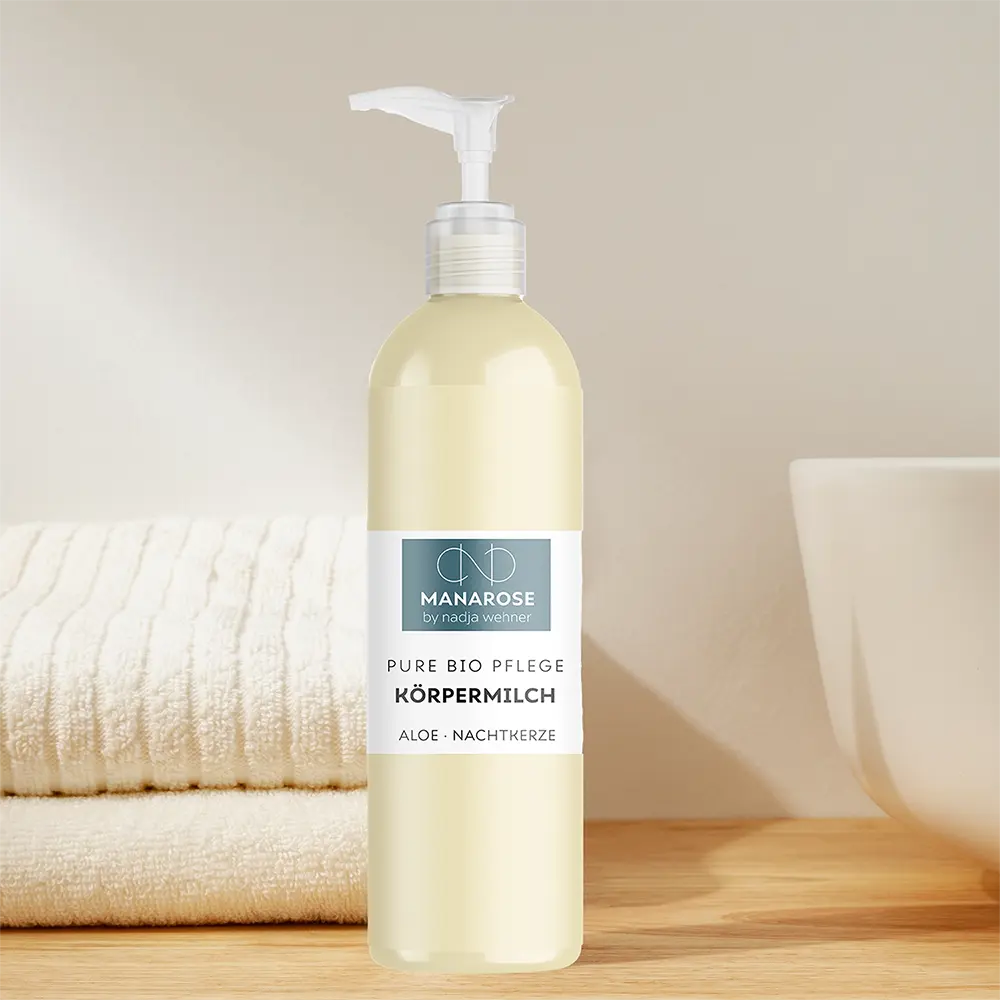 Eine Flasche Körpermilch Aloe Nachtkerze von Manarose Biokosmetik neben einem Handtuch auf einem Holztisch.