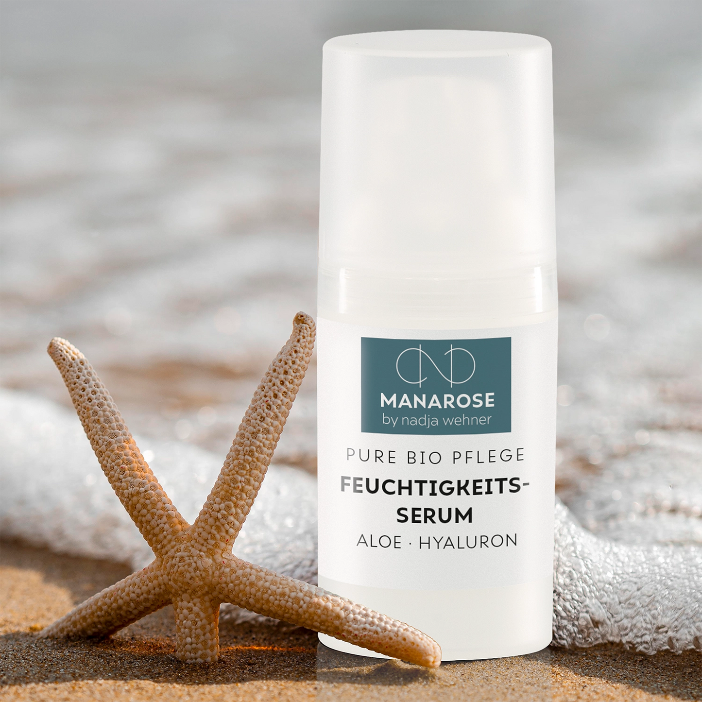Ein Seestern am Strand neben einer Flasche Feuchtigkeits-Serum Aloe Hyaluron von Manarose Biokosmetik.