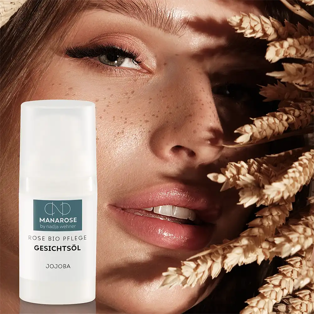 Eine Frau mit anspruchsvoller Haut hält eine Flasche Manarose Biokosmetik Gesichtsöl Rose Jojoba Creme vor einem Weizenfeld.