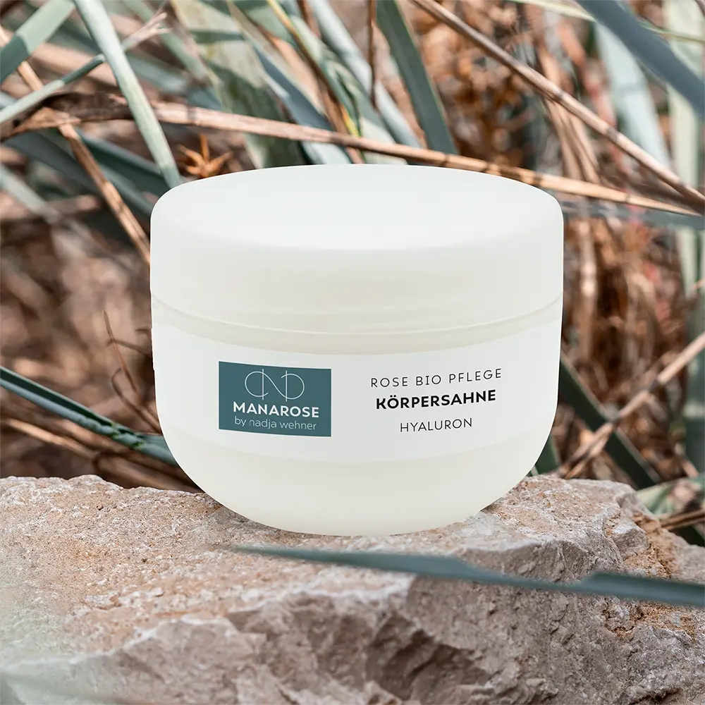 Ein Glas körperahne Rose Hyaluron von Manarose Biokosmetik auf einem Felsen platziert, sorgt für ein luxuriöses Hautgefühl.