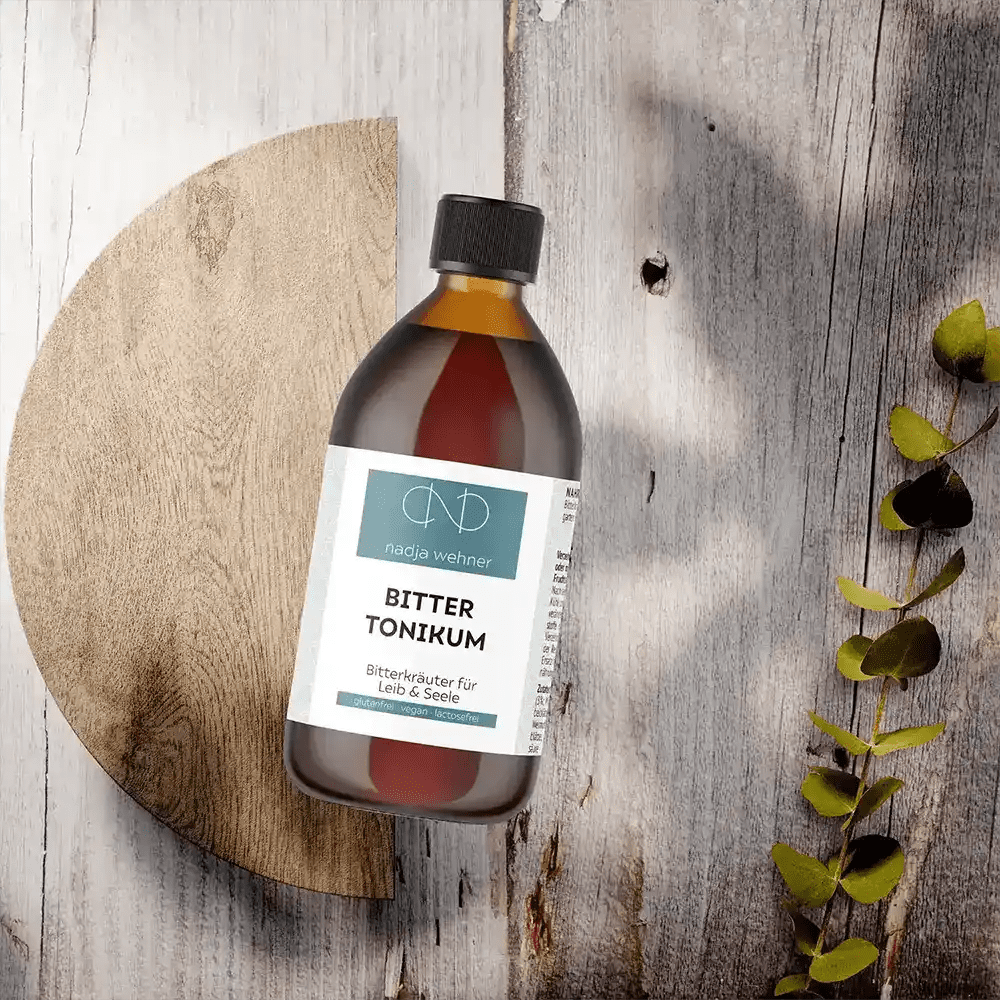 Eine Flasche Manarose Bitter Tonikum-Öl steht auf einem Holztisch.