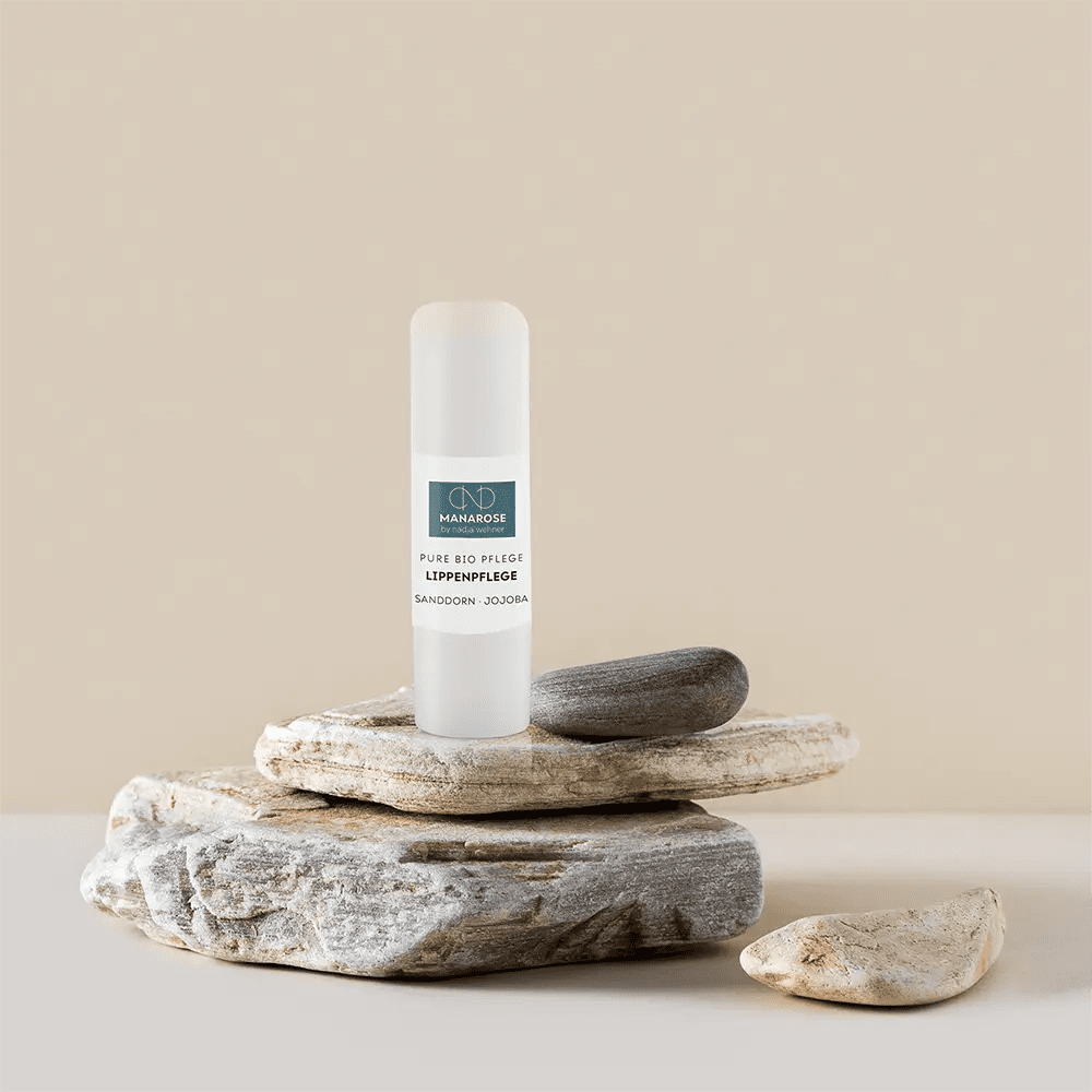 Eine Tube Manarose Biokosmetik Lippenpflege Sanddorn Jojoba sitzt auf einem Felsen.
