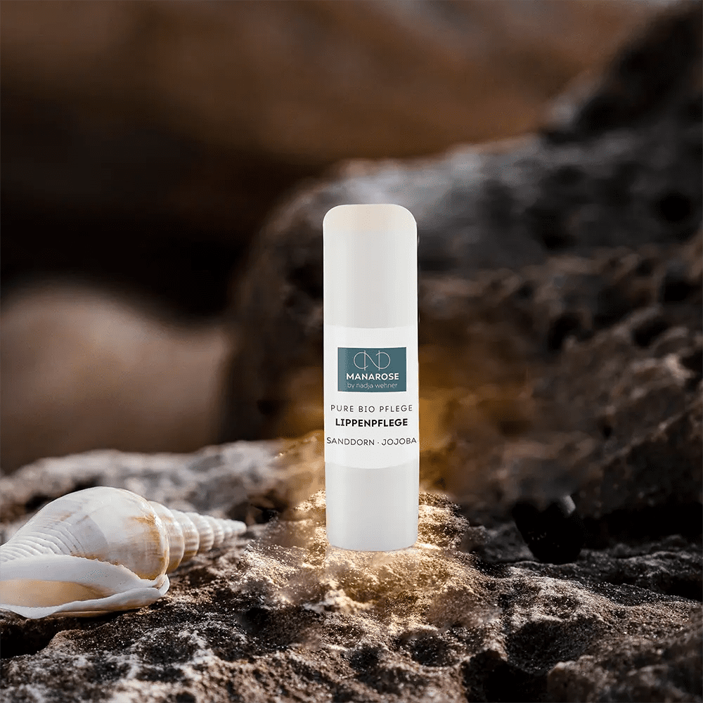 Eine Tube Lippenpflege Sanddorn Jojoba von Manarose Biokosmetik, eine natürliche Luxus-Lippenpflege, platziert auf einem Felsen.