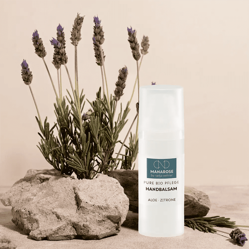 Eine Flasche Handbalsam Aloe Zitrone mit beruhigenden Lavendelpflanzen davor, sorgt für natürliche Luxushandpflege mit Manarose Biokosmetik.
