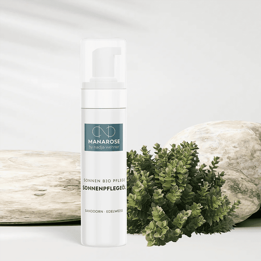 Eine Flasche Sonnenpflegeöl Sanddorn Edelweiß von Manarose Biokosmetik neben einer Pflanze und Steinen fördert eine sichere Hautpflegeroutine.