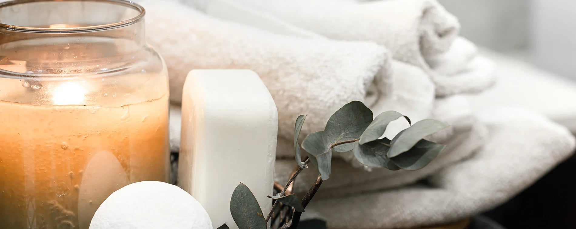 Weiße Handtücher mit einer Kerze und Seife und ein Eucalyptus Ast