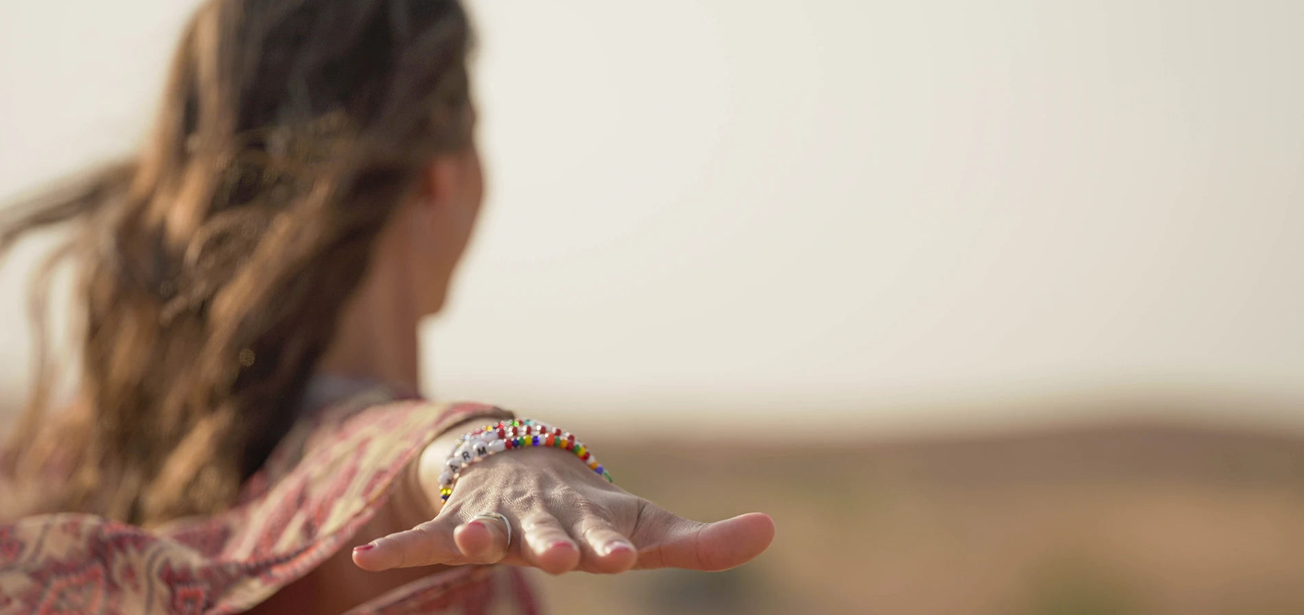 Eine junge Frau steht in der Wüste mit ausgestreckten Händen 
